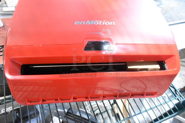Red Georgia Pacific enMotion wall-mounted paper towel dispenser, new with minor scratches, shows logo and sensor area.