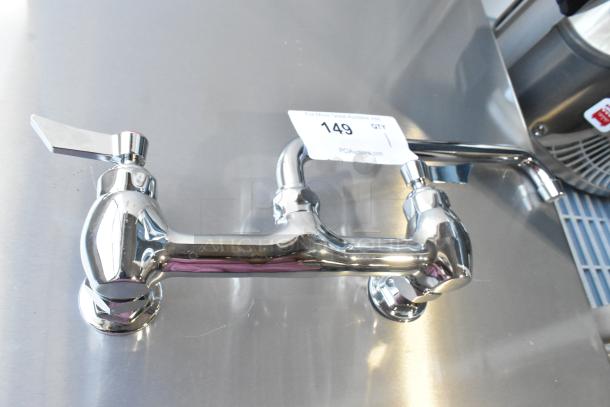 Chrome kitchen faucet with dual handles, brand new but has visible scratches. Auction tag with item number 149 attached.
