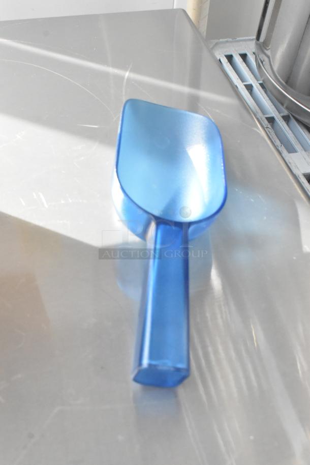 Blue plastic scoop on metal surface, reflecting light.