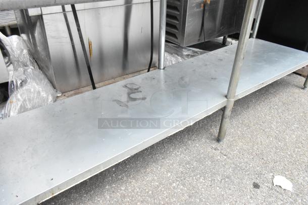 Stainless steel table with mounted commercial can opener, includes metal under shelf. Some rust present. Suitable for heavy-duty use.