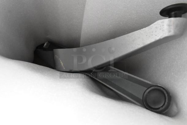 Silver powder-coated aluminum table leg showing minor scratches, part of a Lancaster dining set, in packing foam.