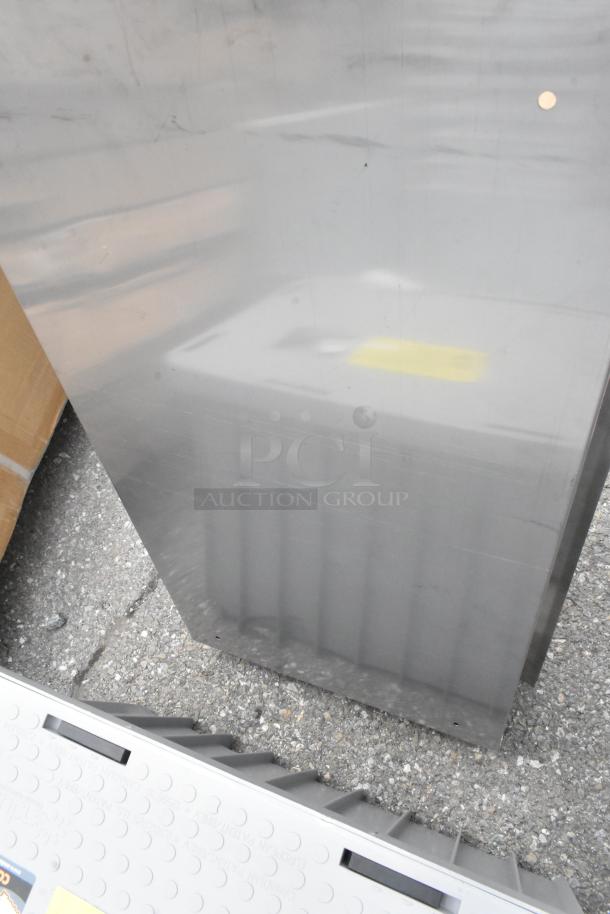 Brand new stainless steel toilet paper dispenser, showing noticeable scratches and dents on the surface.