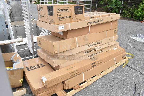 Boxes of brand new scratch and dent items, including Steelton speed rail and Cambro post kits, stacked on a pallet.