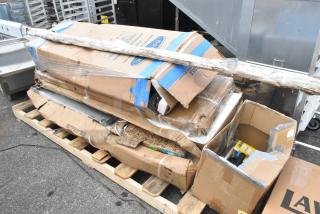 Boxes of Regency stainless steel scratch and dent items on a pallet, including pass-through shelves and commercial tables.
