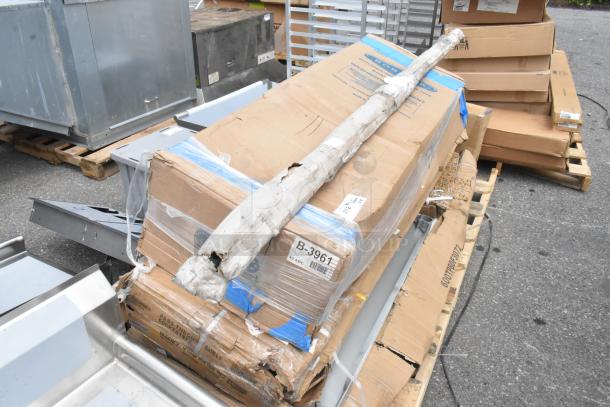 Damaged packaging containing Regency stainless steel tables and shelves, tagged "B-3961." Items appear new but scratched.