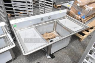 BRAND NEW Regency 600S12424218 stainless steel sink with single bay and dual drain boards. Slight dents visible.