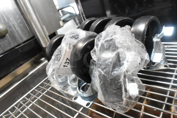 Lot of 8 commercial casters, brand new with minor scratches, wrapped in plastic. Metal plates visible. Quantity tag shown.