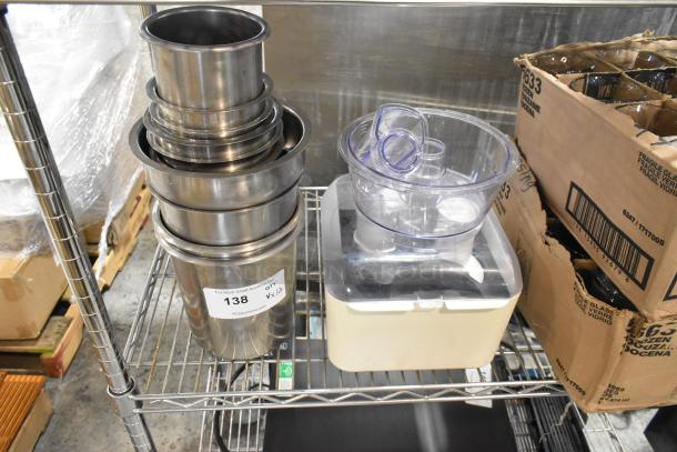 Brand new stainless steel cylindrical drop-in bins and food processor parts on a metal shelf. Auction tag marked "138."