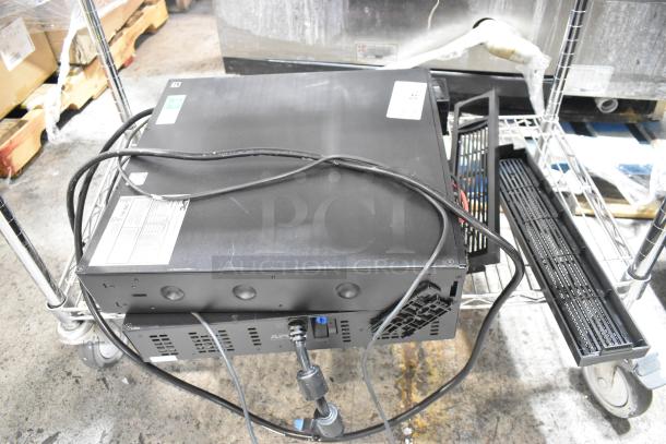 Two APC Uninterruptible Power Supplies on a metal cart, each showing cables and ports. No visible damage. Tags display model specifics.
