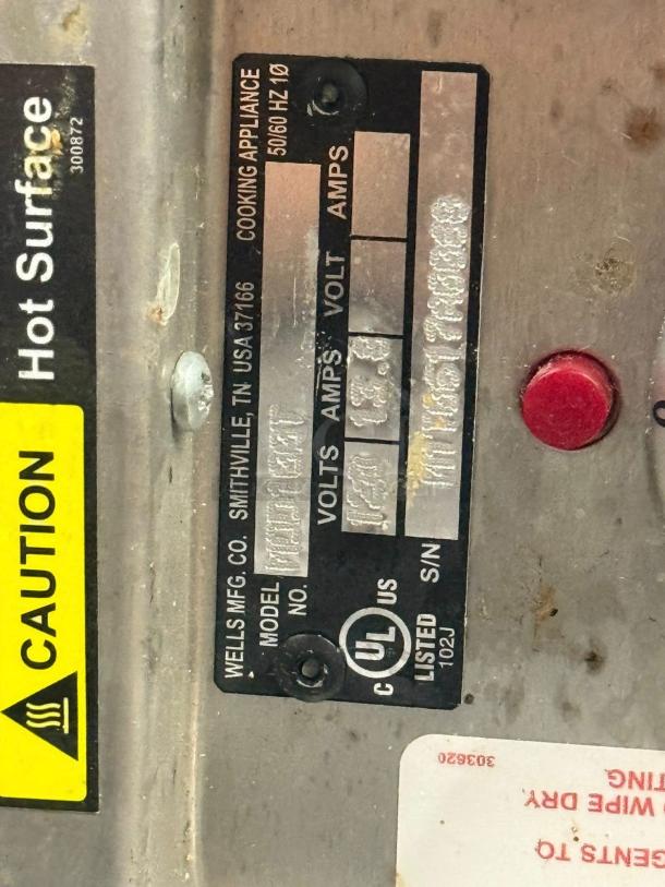 Wells drop-in food warmer label indicating model, voltage, and UL certification. Caution sign visible.