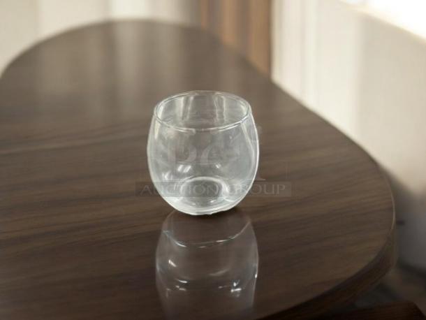 Clear votive candle holder in stemless goblet style, great condition, on a wooden table.