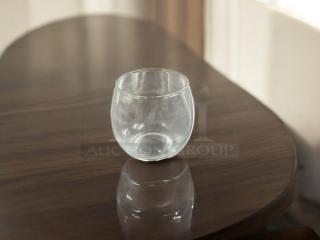 Clear votive candle holder in stemless goblet style, great condition, on a wooden table.