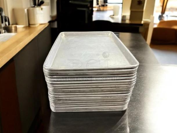 Stack of half-size bakery sheet pans, 13x18x1 inches, in excellent condition on a countertop.
