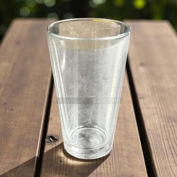 12 oz glass drinking cup in excellent condition, clear with slight reflections, shown on a wooden table.