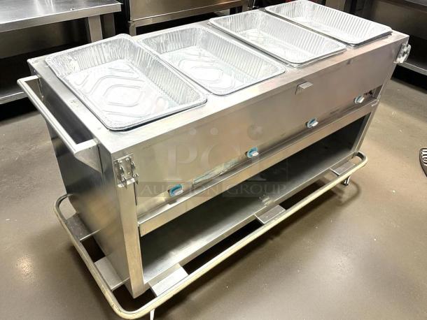 Stainless steel commercial food warmer with four aluminum pans, temperature controls, under-shelf storage, and sturdy handles.