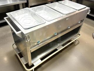 Stainless steel commercial food warmer with four aluminum pans, temperature controls, under-shelf storage, and sturdy handles.