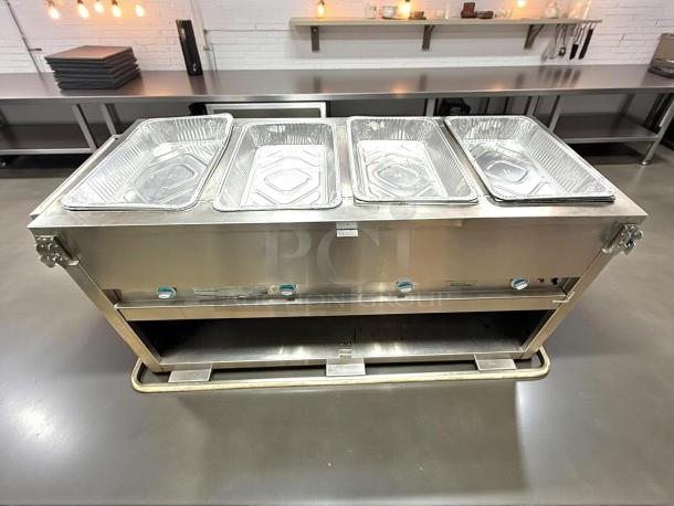 Stainless steel commercial steam table with four chafing pans, adjustable knobs, and shelf below. Good condition.