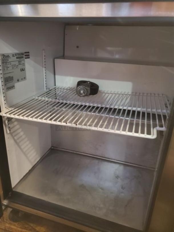 True TSSU-72-16 72" Sandwich/Salad Prep Table, visible internal storage, label with model details, worn casters.