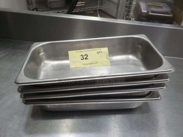 Lot of 4 stainless steel food pans, stacked. Each in good condition, suitable for commercial use. Auction label reads "32 QTY 4."