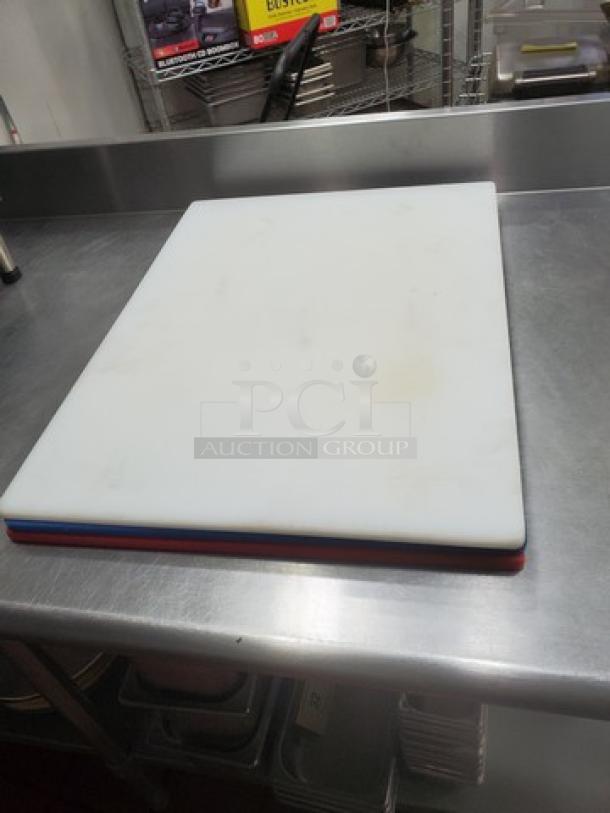Lot of 3 plastic cutting boards stacked, in used condition; white, red, and blue colors visible.