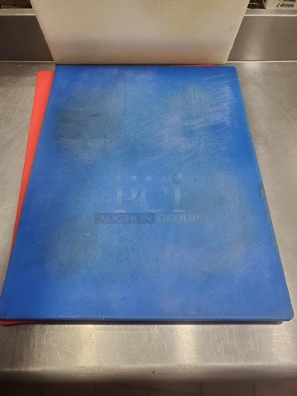Lot of 3 cutting boards; red, blue, and white; visible wear and scratches; suitable for kitchen use.
