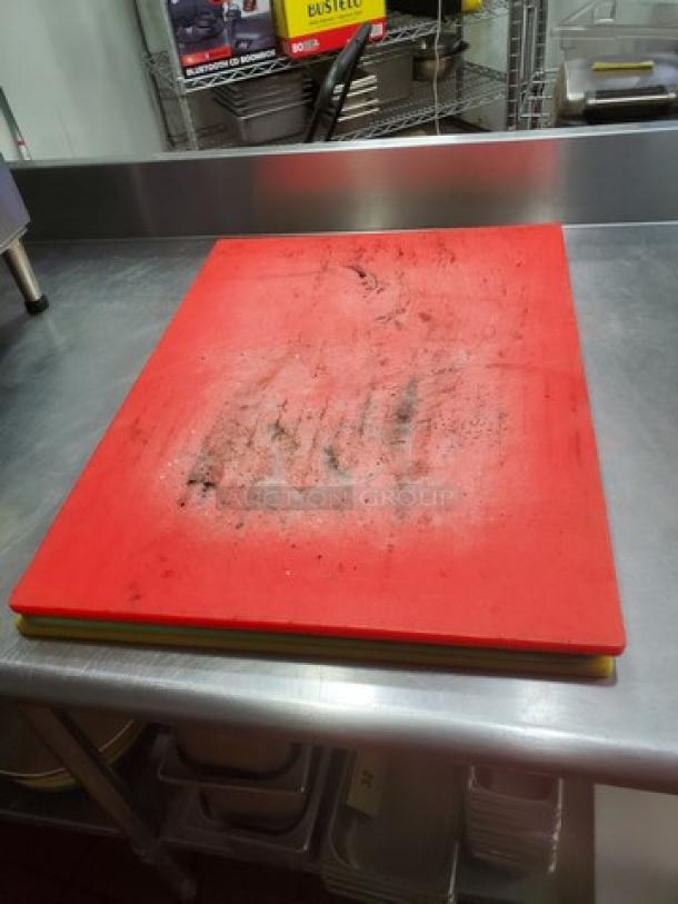 Lot of 3 cutting boards, various colors, used condition with visible scratches and marks, stacked on stainless steel surface.