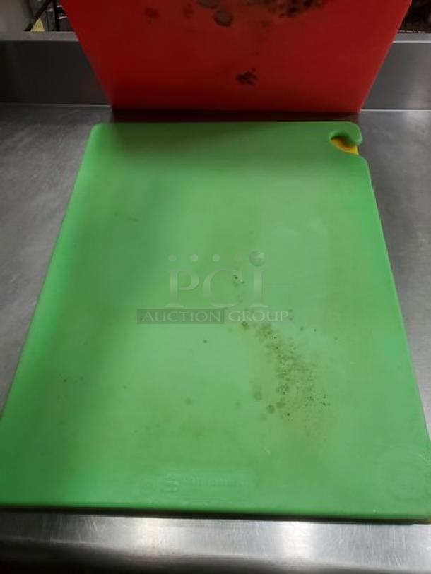 Lot of 3 cutting boards; visible red and green boards with surface wear; one board features a handle cutout.