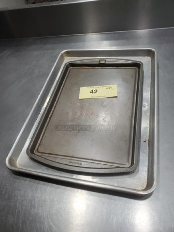 Lot of 2 metal baking trays, varying sizes, used condition with slight wear. Auction label with number "42" on top tray.
