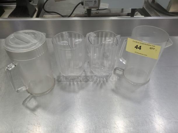 Lot of 4 plastic pitchers, clear design, each with a spout and handle. Includes one lidded pitcher. In good condition.
