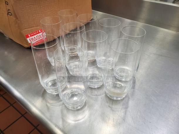Lot of 19 clear glass tumblers displayed on a metal surface. Glasses appear in good condition with no visible markings.