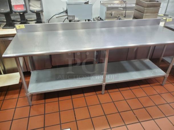 96" stainless steel work table, features a backsplash, undershelf, and sturdy legs. Ideal for commercial kitchens.