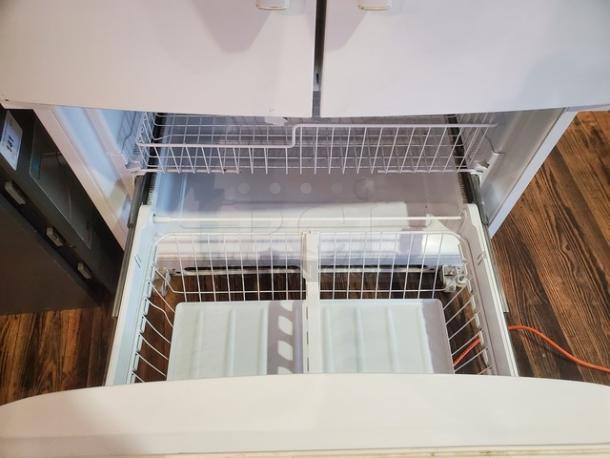 Whirlpool GX5FHTXVQ06 24.8 cu. ft. French door refrigerator with pull-out freezer drawer open, showing wire baskets.