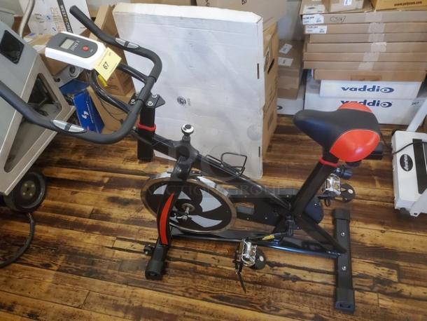 Mini cycling exercise bike with digital display, black and red design, in good condition. Ideal for indoor workouts.
