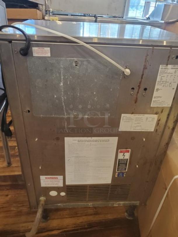 Ice-O-Matic ICEU220HA3 commercial undercounter ice maker, visible wear, various labels affixed detailing model info and warnings.