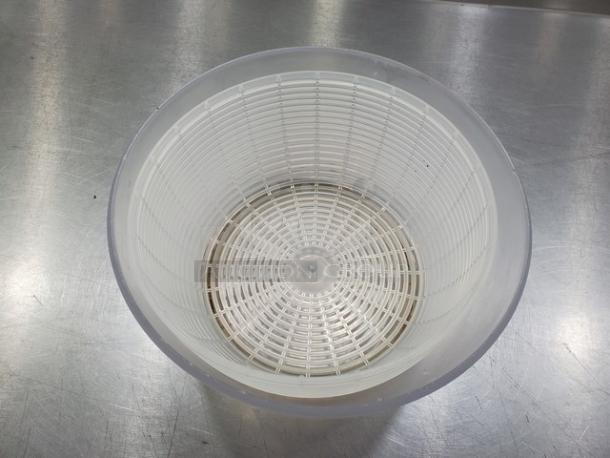White plastic salad spinner in good condition, featuring a mesh basket design for efficient water drainage.