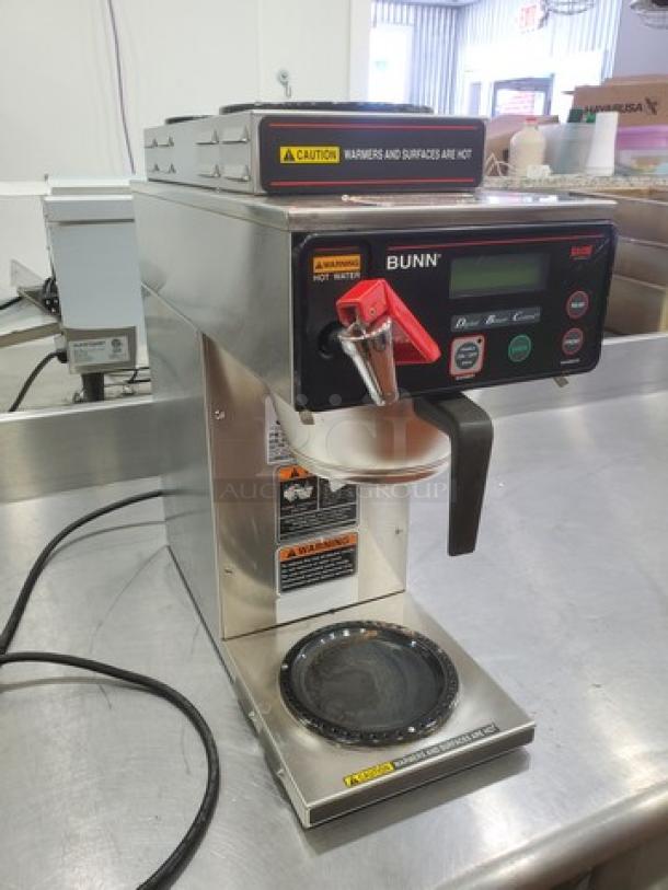 Bunn AXIOM DV-3 coffee brewer with two upper and one lower warmer, stainless steel body, digital display, warning labels visible.