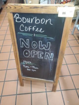 Wooden framed chalkboard sign for "Bourbon Coffee," marked "Now Open" with hours "Tues. - Thurs. 8am - 2pm."