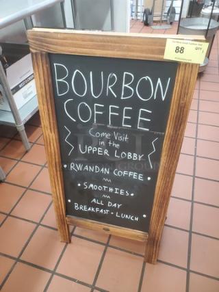 Wooden sandwich board sign with black chalkboard displaying: "Bourbon Coffee, Rwandan Coffee, Smoothies, Breakfast - Lunch."