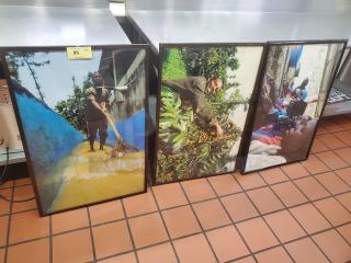 Lot of 3 framed pictures depicting various scenes, set against colorful backgrounds, displayed on a tiled floor.