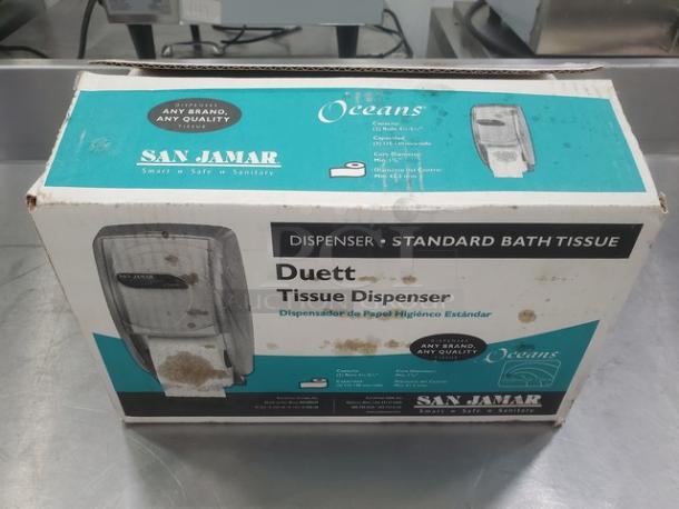 San Jamar Duett Tissue Dispenser in original box, for standard bath tissue. Box slightly worn, features brand and product info.