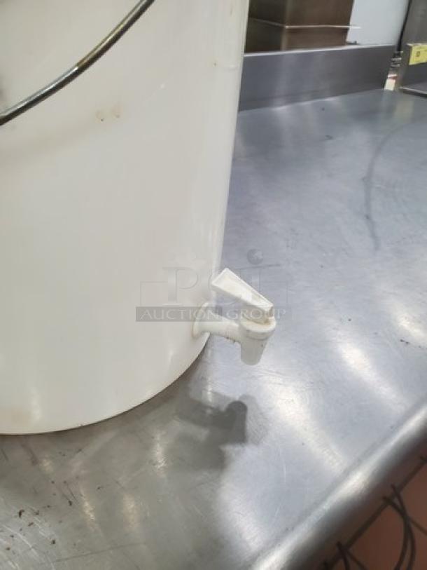 6-gallon white beverage dispenser with spigot, used condition, ideal for cold drinks. Some wear visible on the surface.