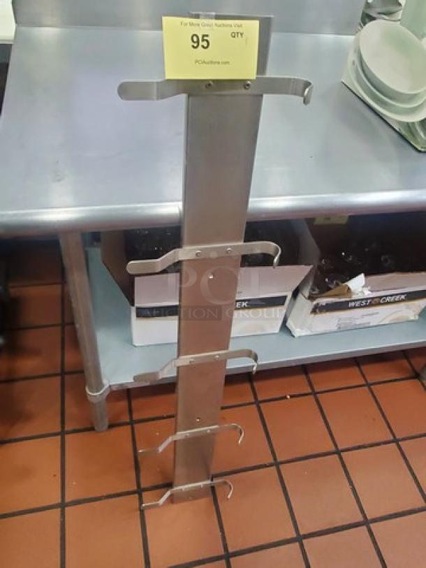 Stainless steel rack with multiple hooks, in good condition, leaning against a counter. Auction tag labeled "95" on top.