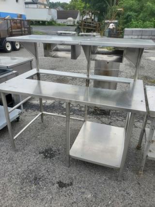 Custom stainless steel work station with upper shelf and lower storage platform. Used condition, durable design, ideal for kitchens or workshops.