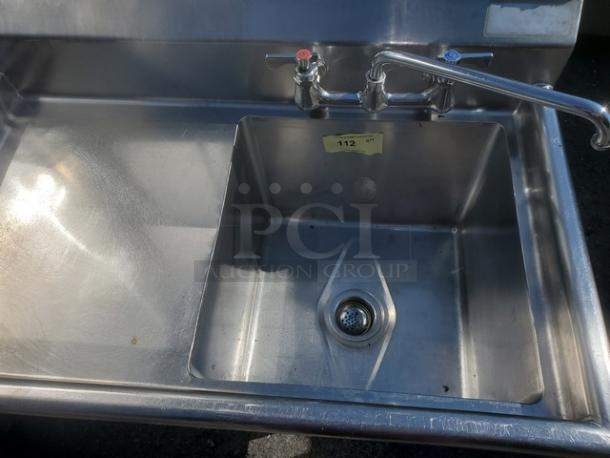 Stainless steel one compartment sink with dual faucet, good condition, ID tag "112".