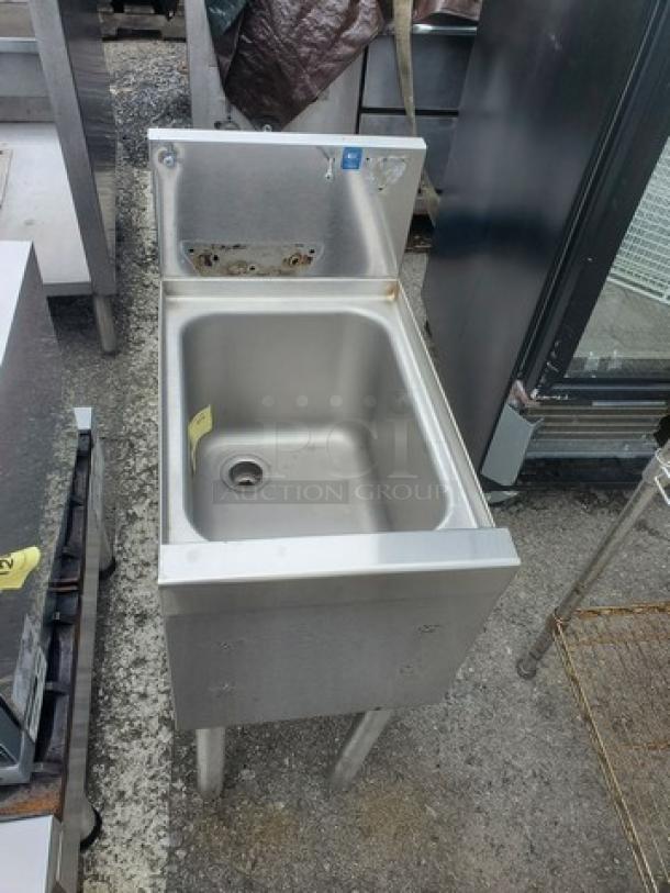 Stainless steel one compartment sink, commercial-grade, with backsplash. Visible mounting holes, good condition.