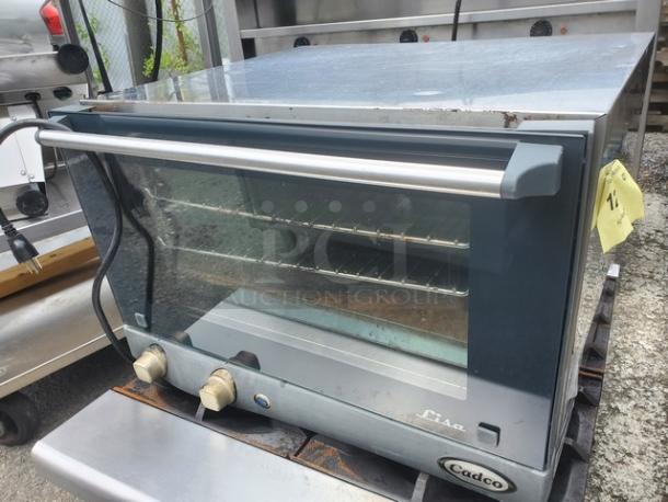 Cadco Uno-X XAF013 countertop convection oven, stainless steel with glass front, features dual dials, visible shelves inside.