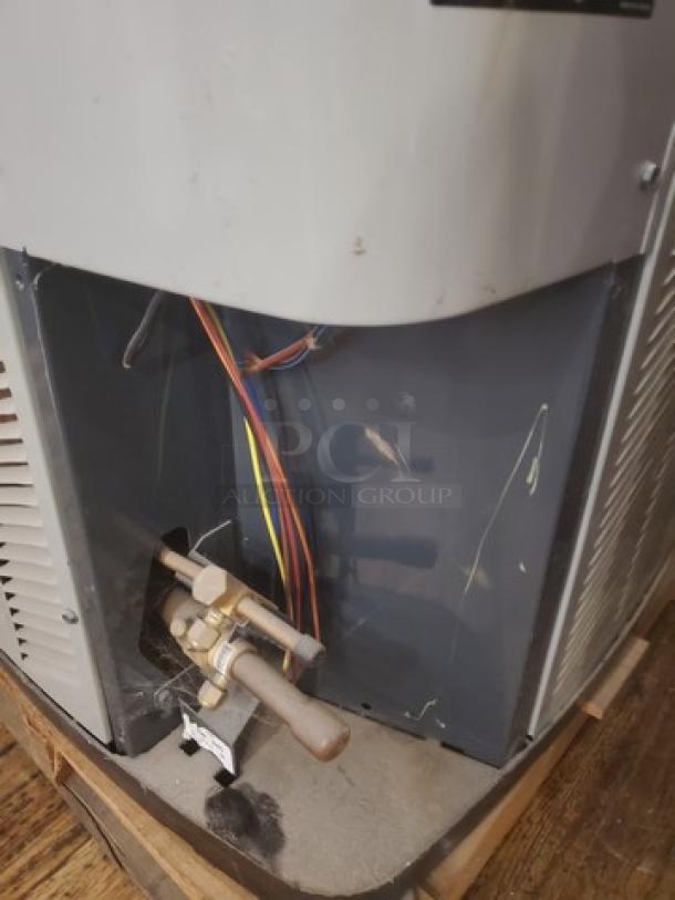 Central Air Conditioner Condenser 2TWB3024A1000AA, exposed wiring, used condition, visible wear on housing, mounted on pallet.