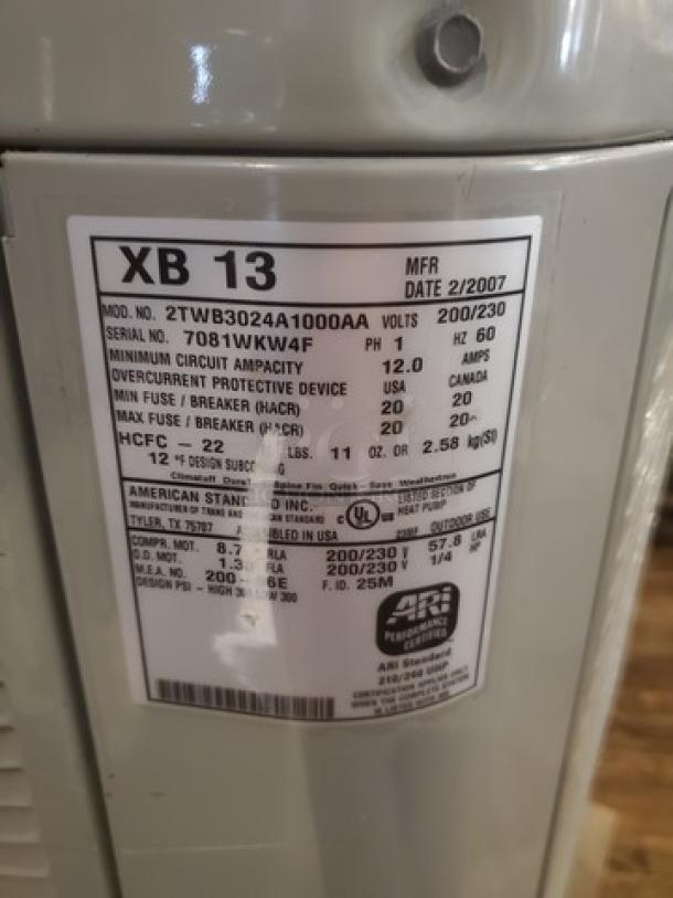 Central air conditioner condenser, model 2TWB3024A1000AA, label shows specs like voltage and manufacturing date 2/2007.