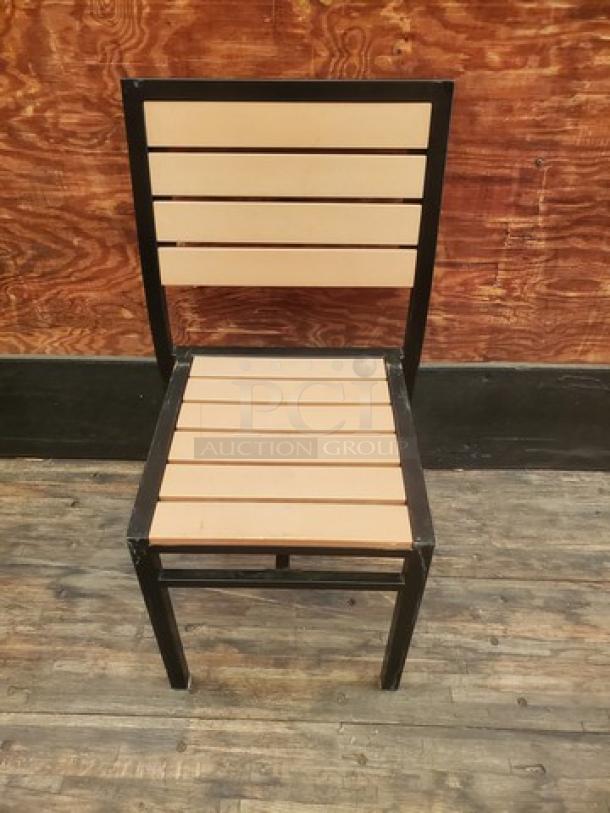 Set of 4 patio chairs with black metal frames and beige slatted seats. Rustic wooden backdrop. Good condition.