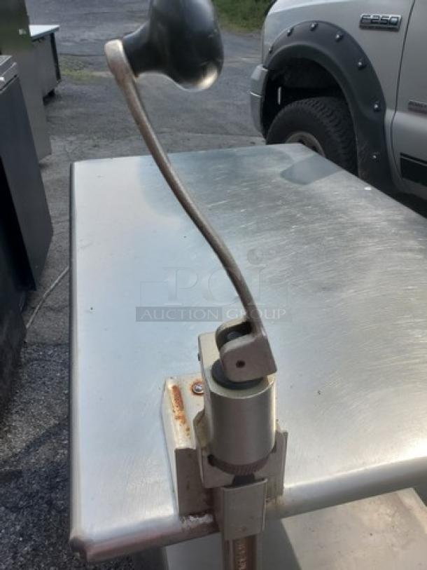 Stainless steel work table with integrated can opener, no drawer, used condition, suitable for commercial kitchens.